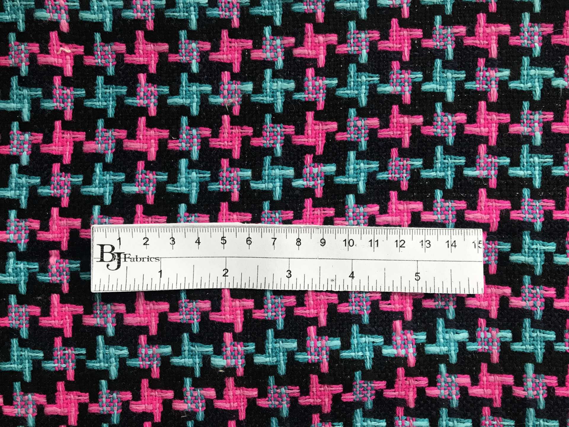 ruler sits on top of tweed to show scale of herringbone pattern