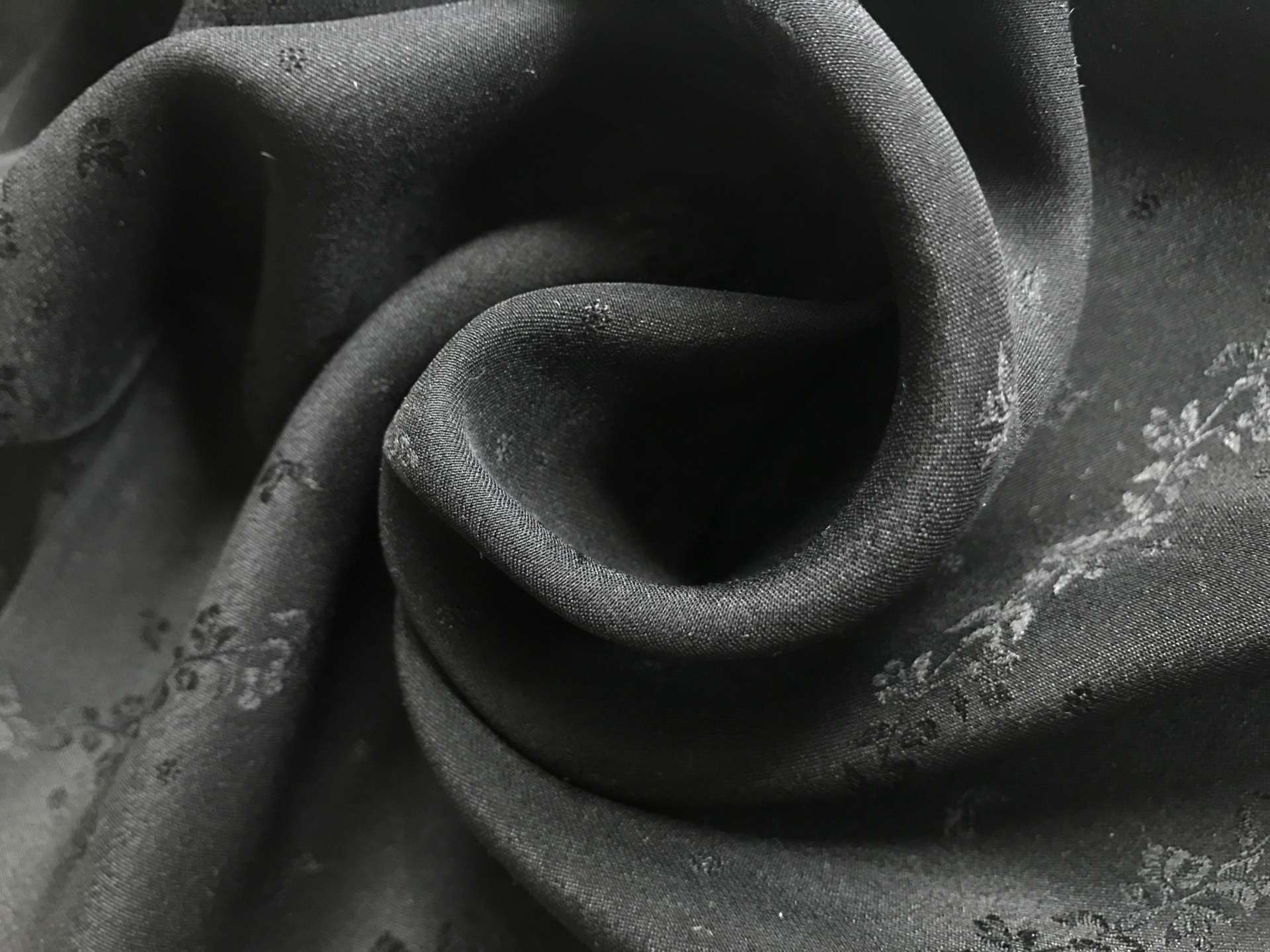 black silk jacquard with rows of vines and florals is in a swirl to show weight and detail