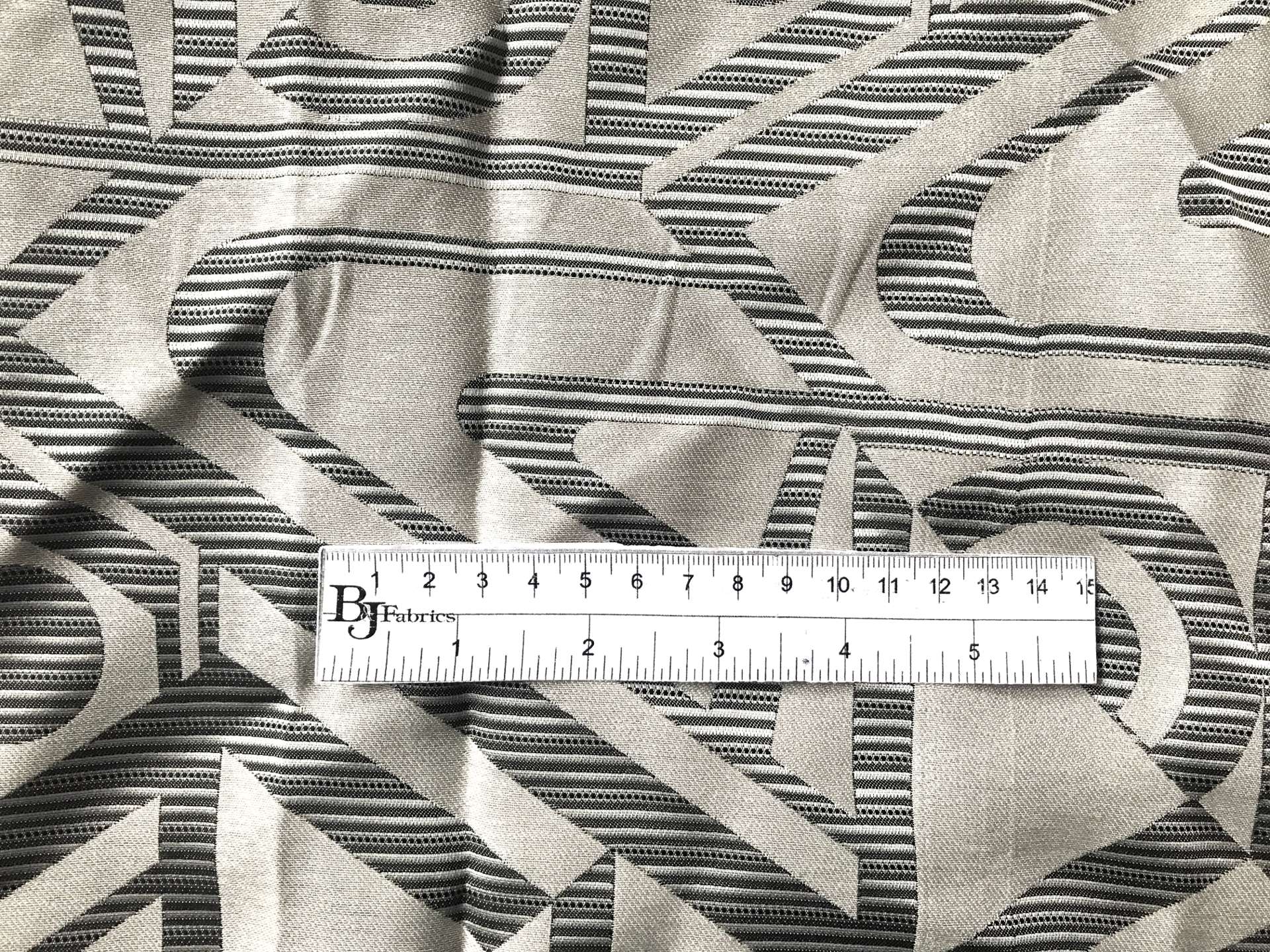 ruler sits on top of geometric brocade to show scale