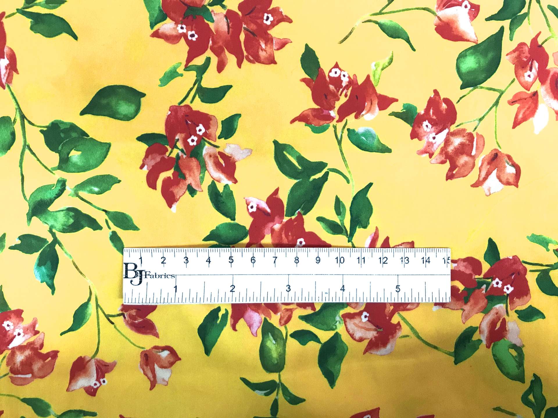 bright yellow, red, green floral cotton and lycra print with ruler to show scale