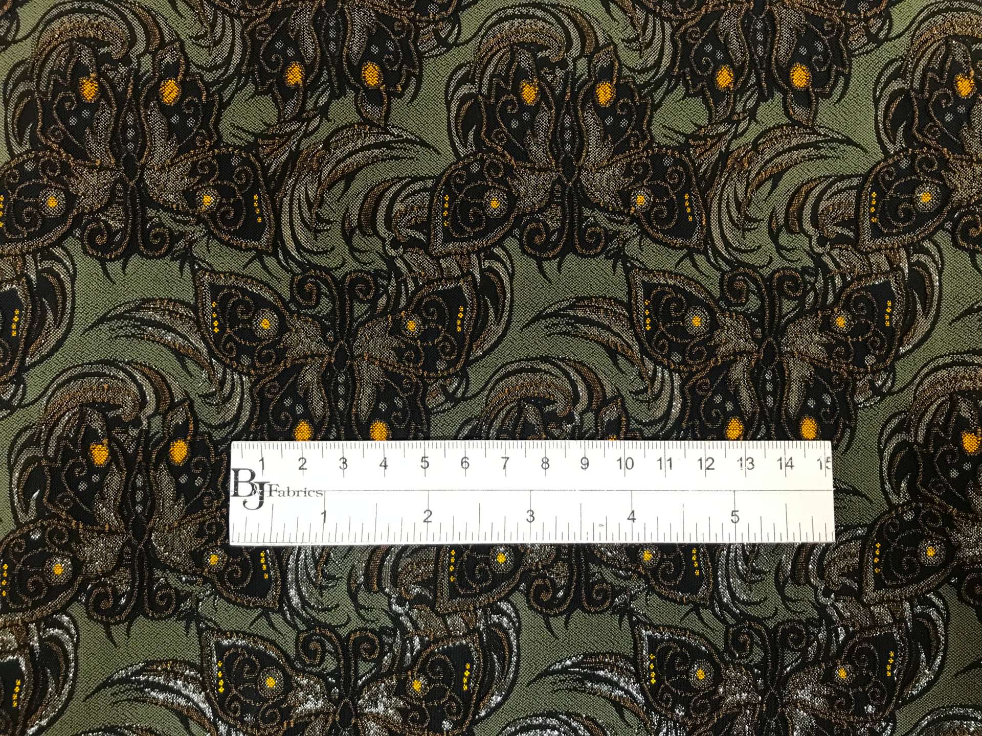 dark green stretch brocade with repeating butterfly pattern with ruler to show scale