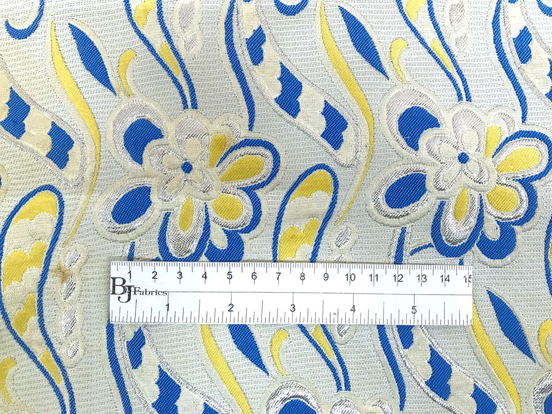 vintage brocade with 60s-esque florals in silver, yellow, and blue with ruler to show scale