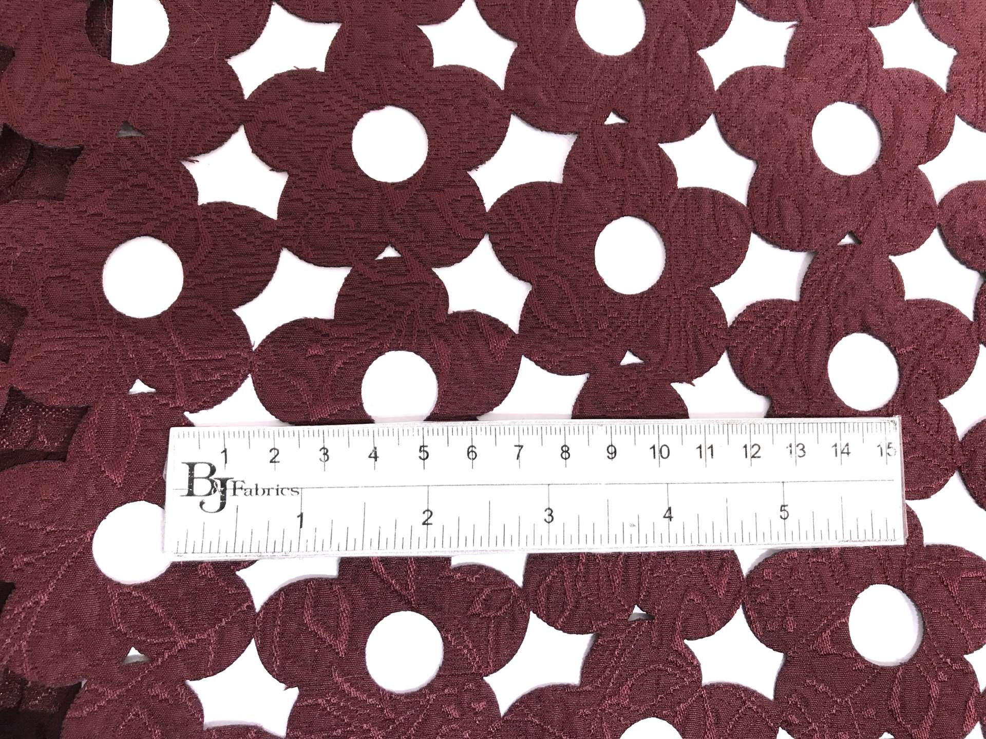 Rayon and Polyester Blend Laser Cut Brocade in Wine with ruler to show scale