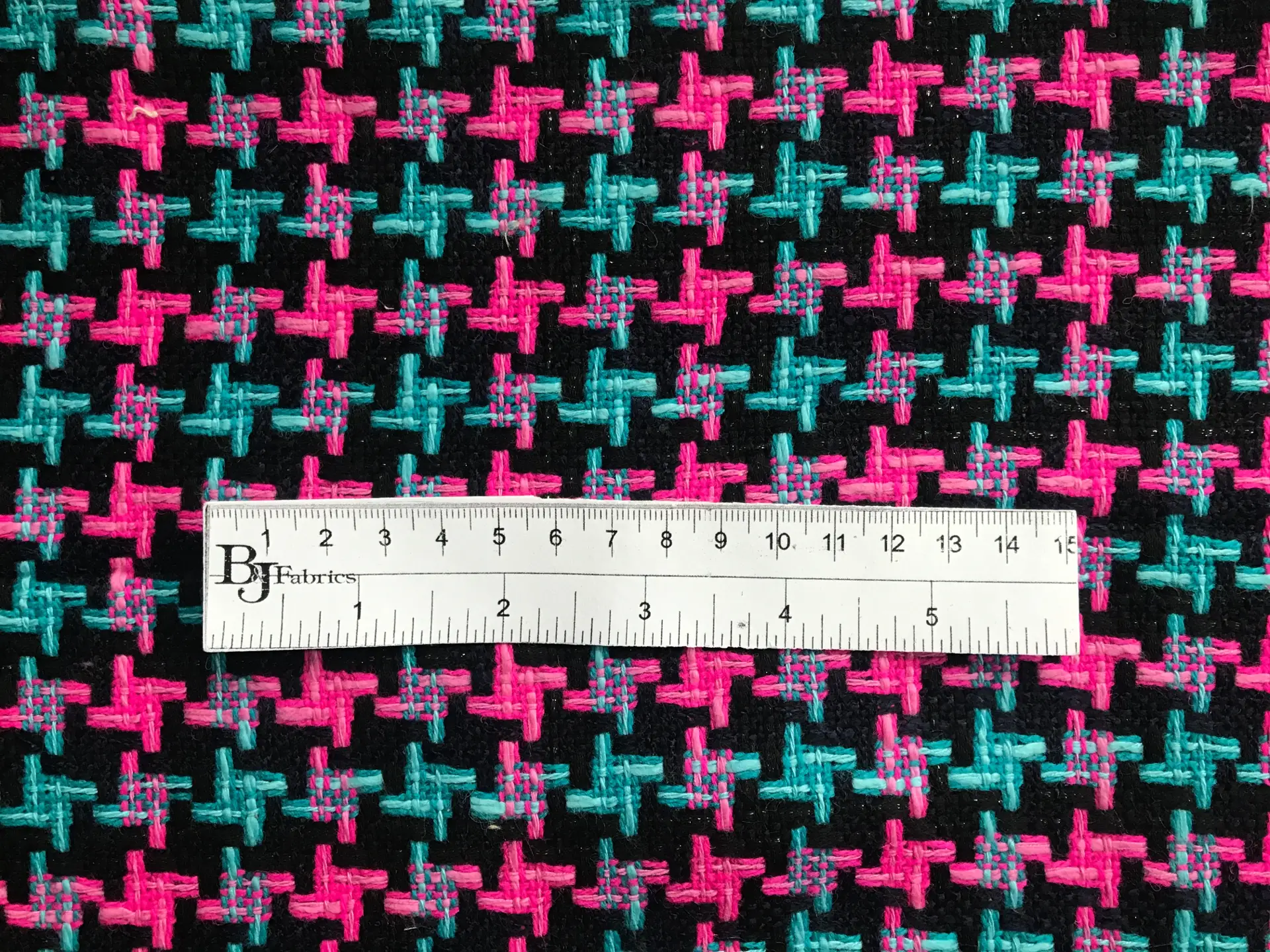 ruler sits on top of tweed to show scale of herringbone pattern