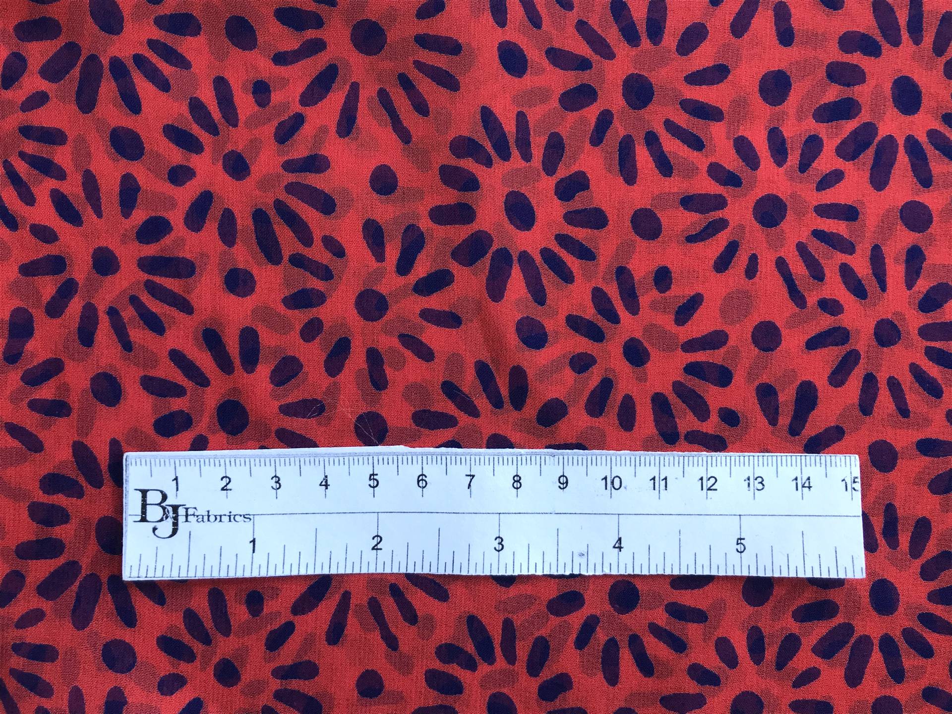 ruler sits on top of red silk chiffon to show the scale of the navy floral pattern