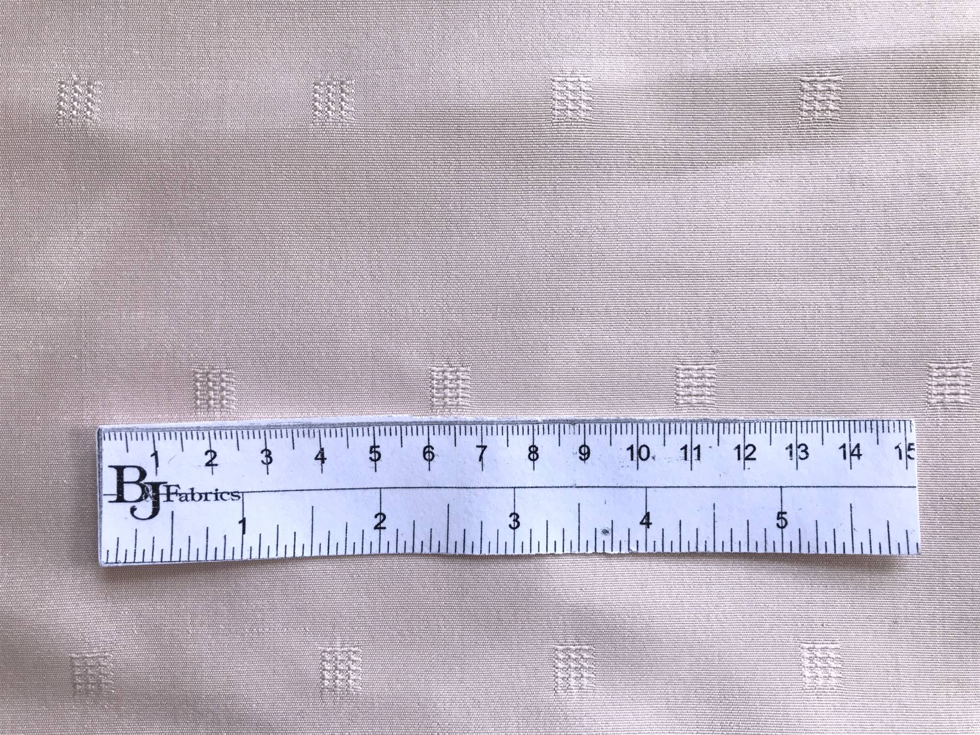 ruler lays on top of blush silk faille with small jacquard squares to show scale of squares