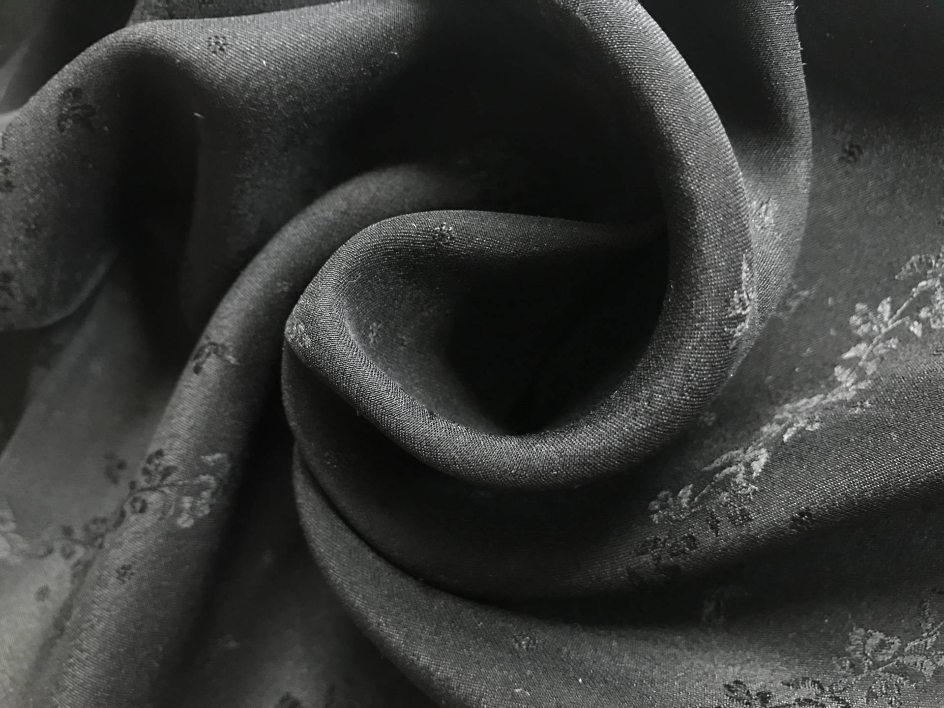 black silk jacquard with rows of vines and florals is in a swirl to show weight and detail