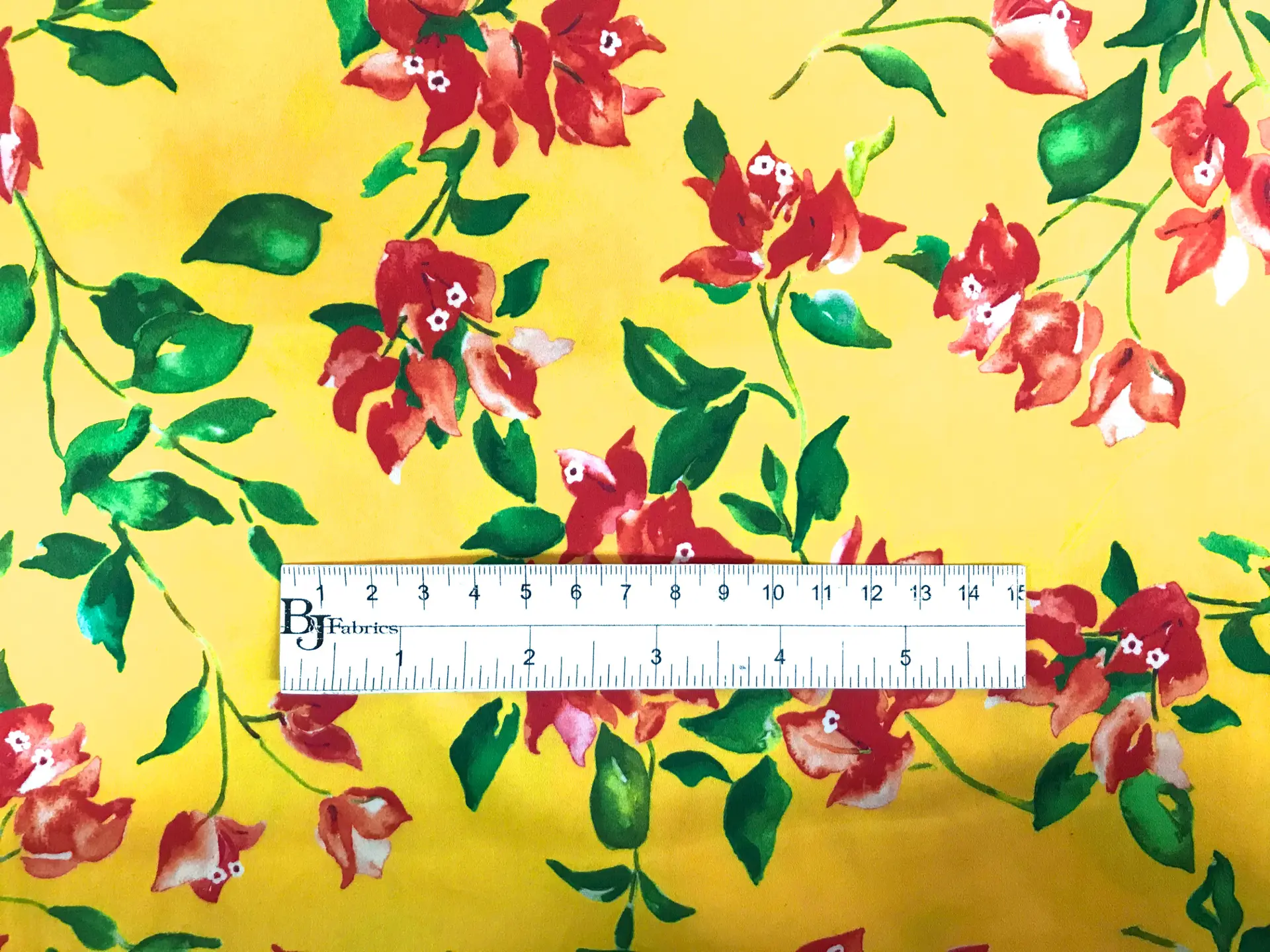 bright yellow, red, green floral cotton and lycra print with ruler to show scale