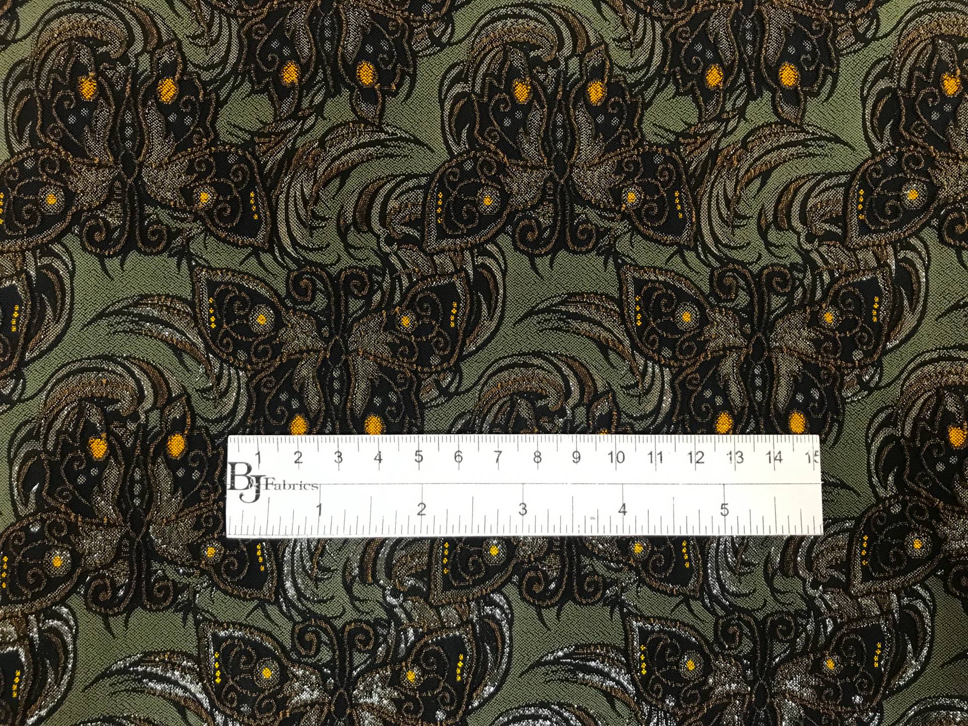 dark green stretch brocade with repeating butterfly pattern with ruler to show scale