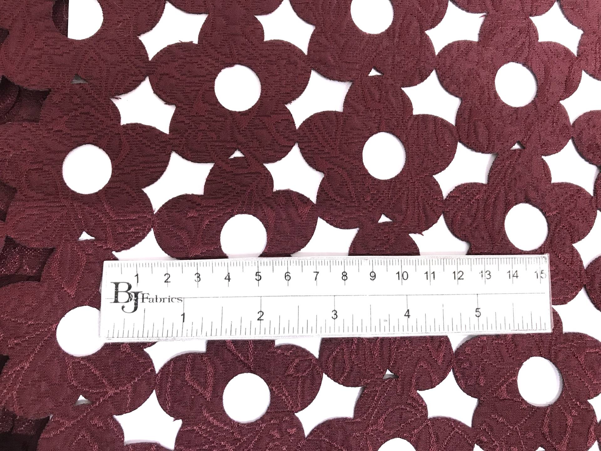 Rayon and Polyester Blend Laser Cut Brocade in Wine with ruler to show scale